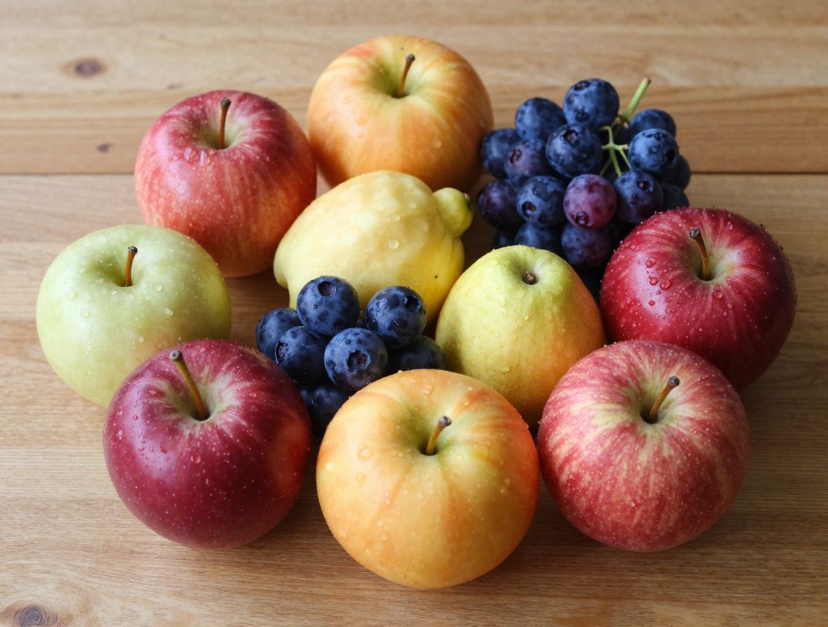 Výběr barevného ovoce a bobulí bohatých na antioxidanty – borůvky, granátová jablka, červené a tmavé plody na tmavém dřevěném povrchu s filmovou estetikou